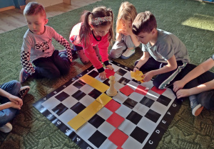dzieci rozkładają kartki na szachownicy